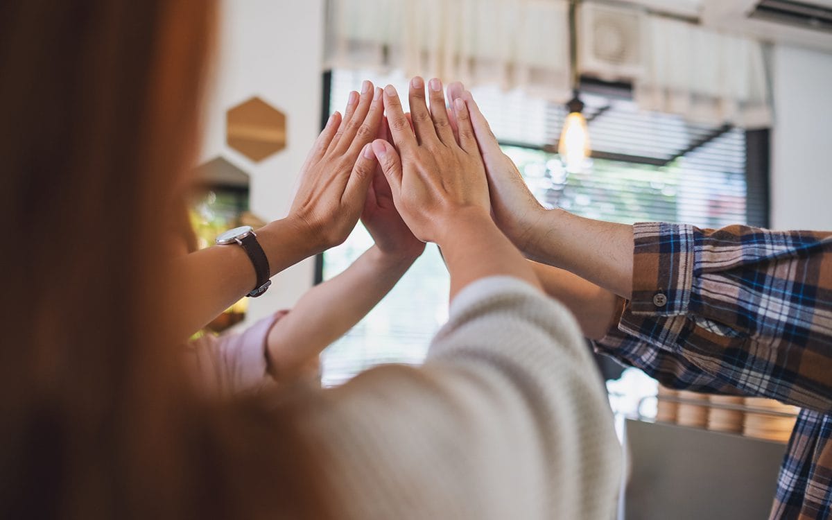 Group of a young business people putting their hands together in the meeting
