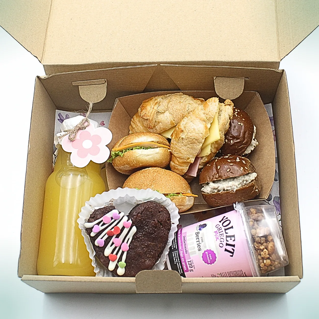 Desayuno Pack Tentación. Desayuno sorpresa en caja kraft con mix de sándwiches, jugo de naranja, yogurt griego y brownie en forma de corazón