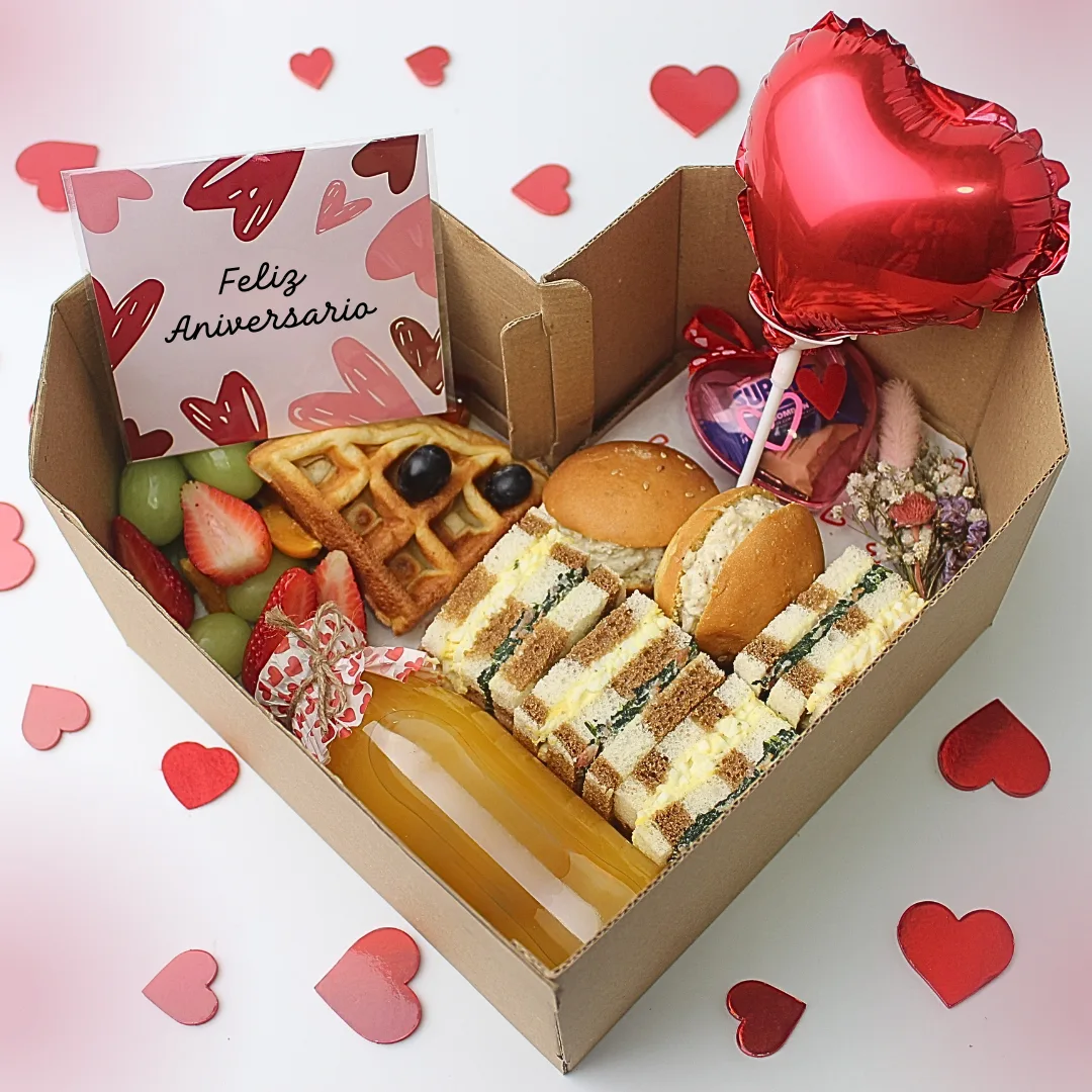 Desayuno Box Forever. Desayuno de aniversario en caja con forma de corazón con wafles, sándwiches triples, petit pan, jugo, flores secas, dulces y globo de corazón rojo