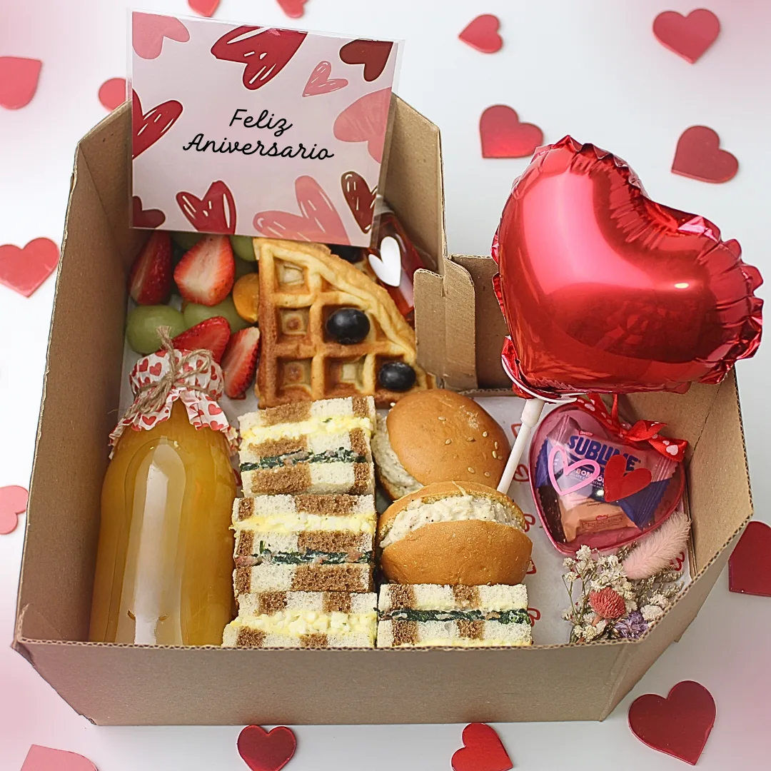 Desayuno Box Forever. Desayuno de aniversario en caja con forma de corazón con wafles, sándwiches triples, petit pan, jugo, flores secas, dulces y globo de corazón rojo