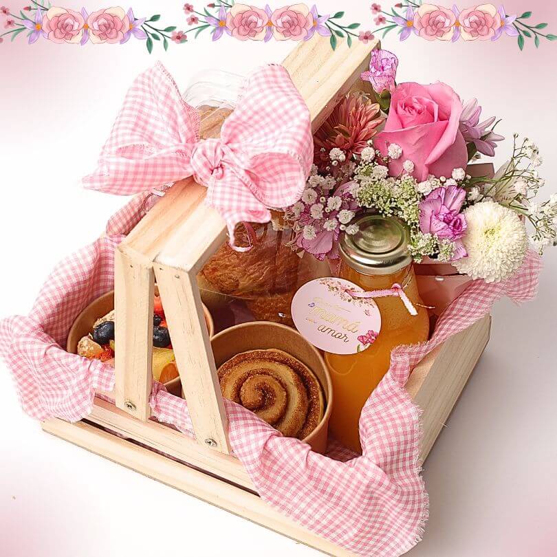 Desayuno Picnic dia de la Madre con flores. Canasta desayuno Día de la Madre con arreglo floral rosa, cinnamon roll, croissant, ensalada de frutas, jugo néctar y tarjeta personalizada en bandeja de pino decorada con tela a cuadros rosada